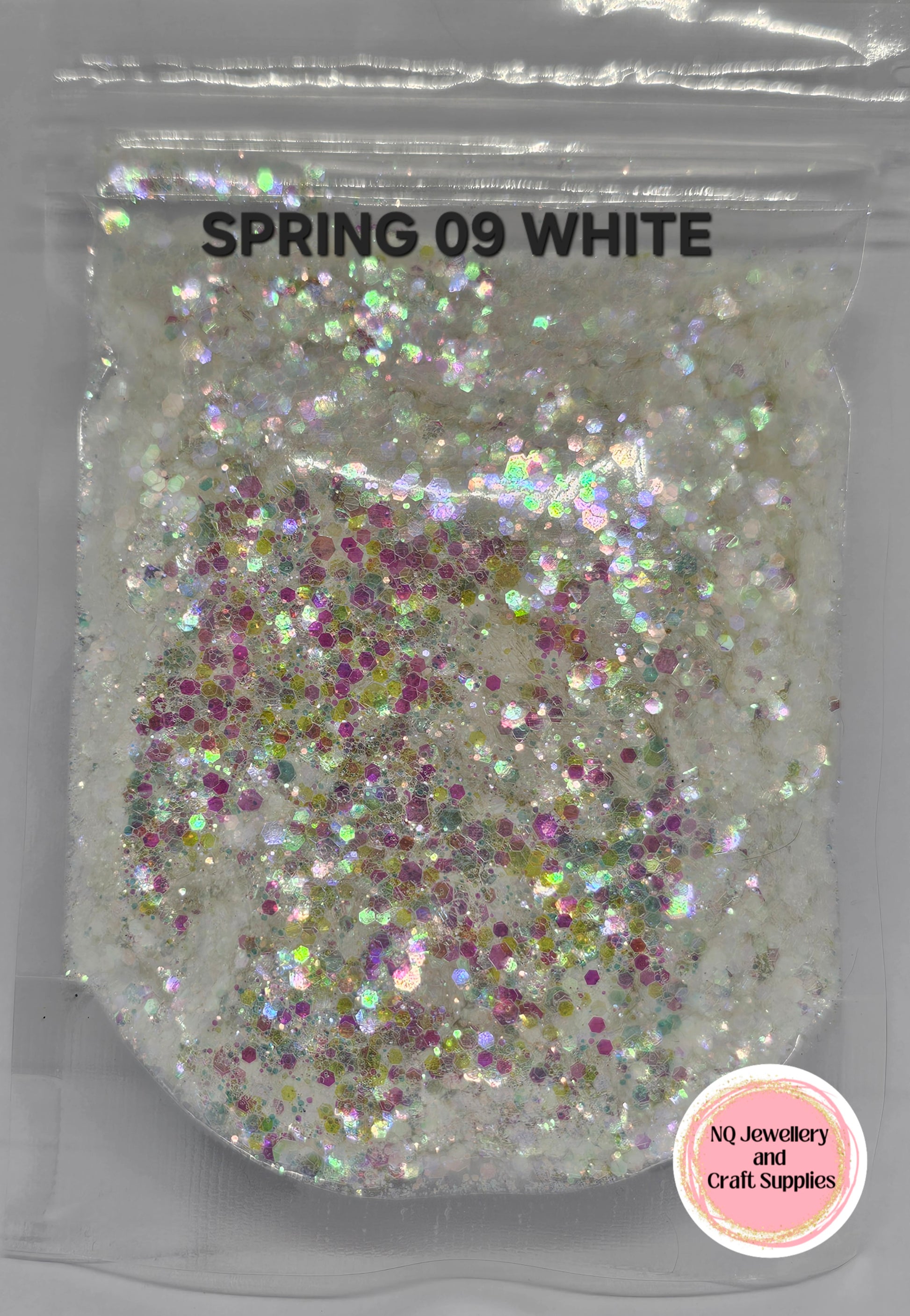 Bag of white glitter labeled 'Spring 09 White' with a brand logo on a clear background